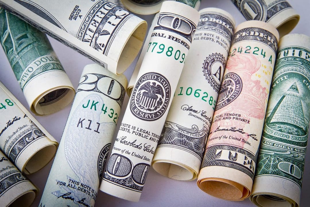 Zwinięte banknoty dolarowe ułożone obok siebie, ilustracja sporu o to, czy Fed obniży stopy procentowe