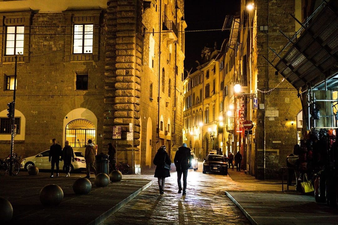 Ludzie spacerują wieczorem historyczną ulicą Florencji wśród zabytkowych budynków, gdy rynek złota spokojnie czeka na podwyżkę Fed.