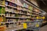 Wózek sklepowy w alejce supermarketu między półkami z nabiałem i artykułami spożywczymi, symbol rosnących cen w USA