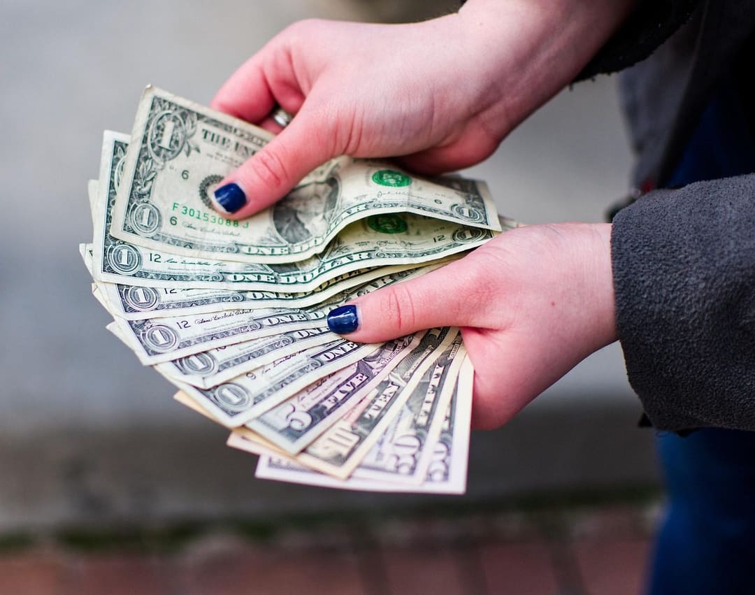 Banknoty dolarowe i gotówka symbolizujące oszczędności i bogactwo, na tle spadku cen złota mimo niższej rentowności obligacji.