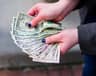 Banknoty dolarowe i gotówka symbolizujące oszczędności i bogactwo, na tle spadku cen złota mimo niższej rentowności obligacji.